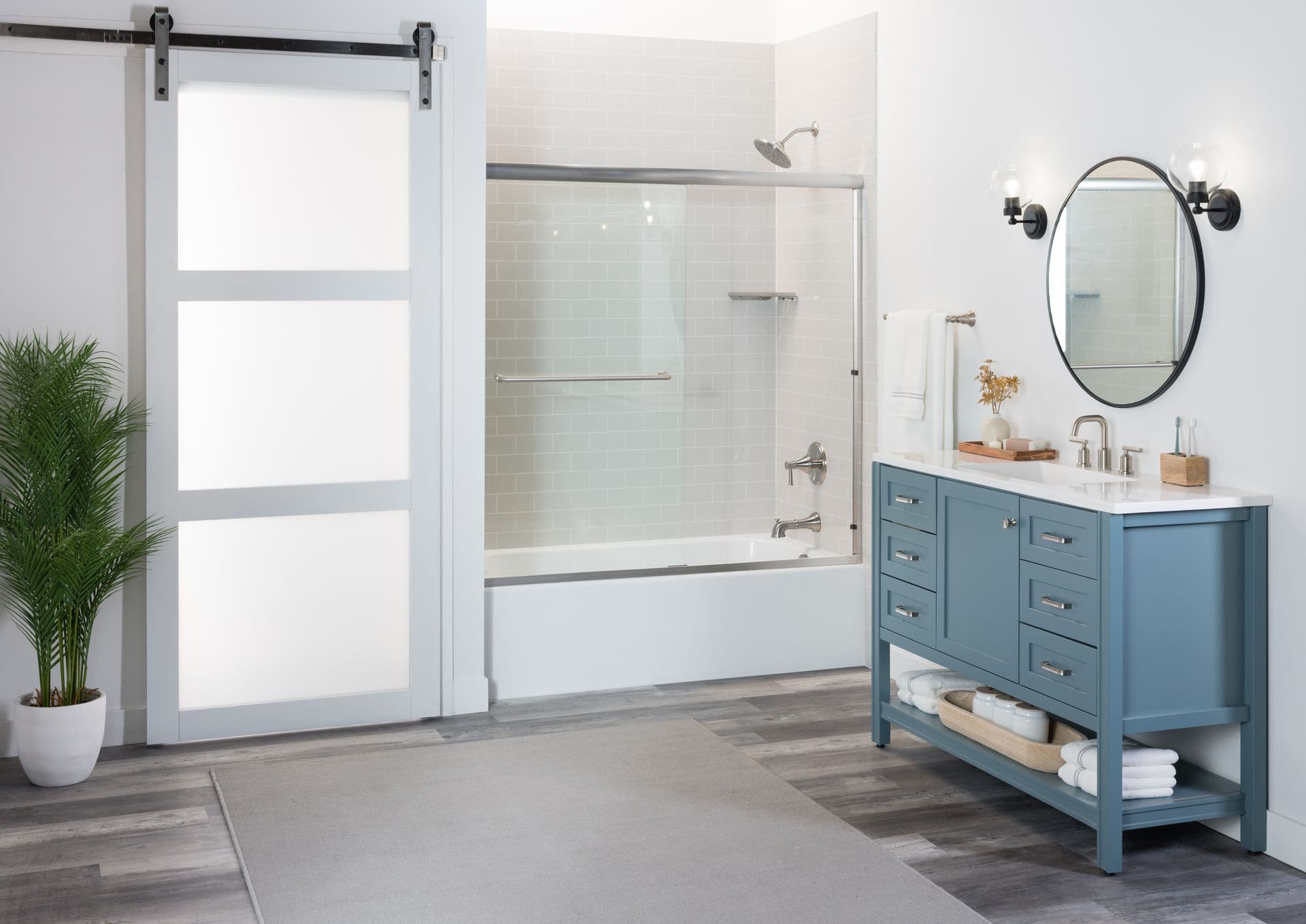 bathtub and shower with blue sink cabinets